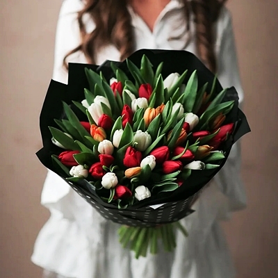 A woman is holding a bouquet with tulip flowers.